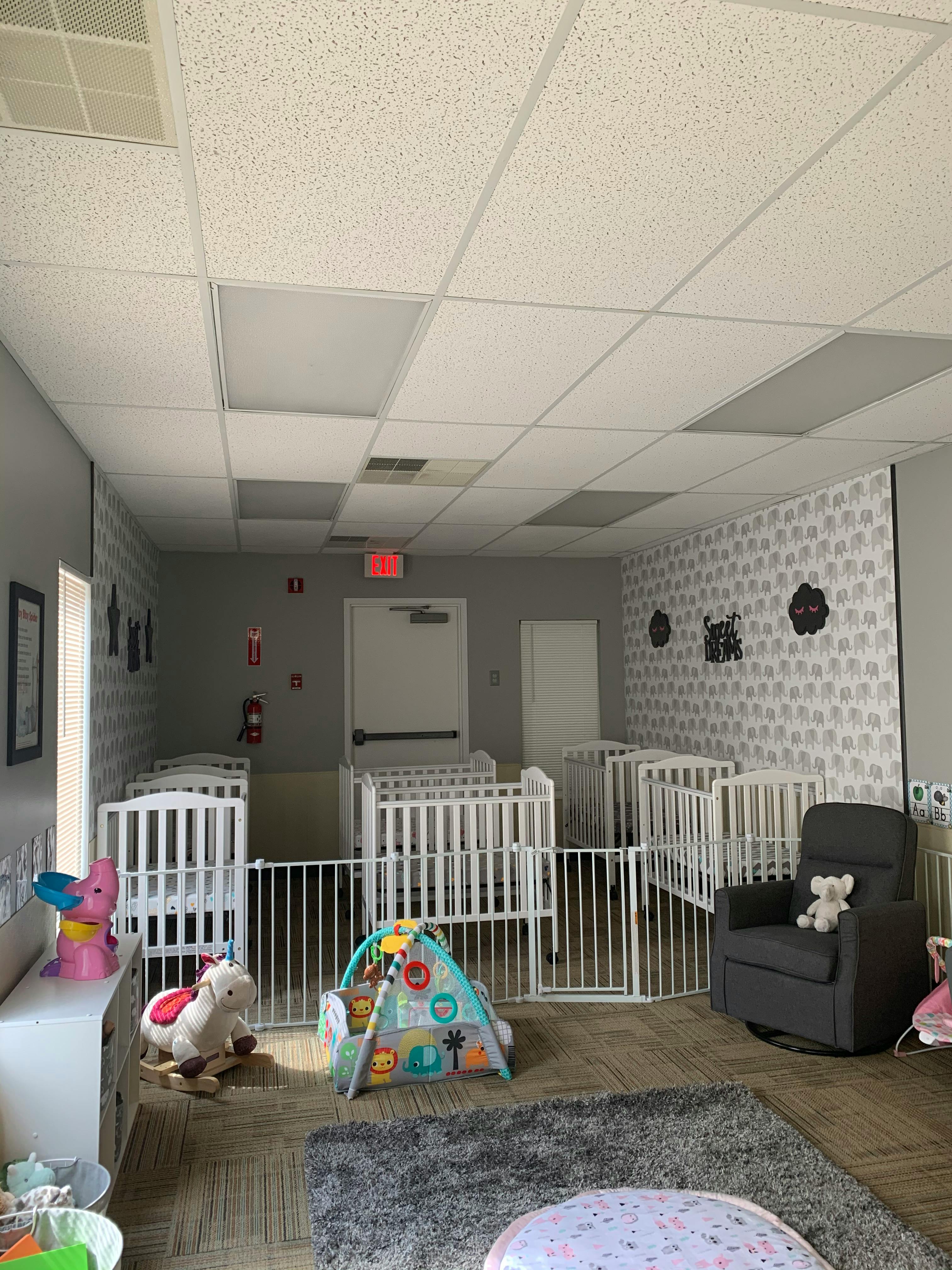 Nursery room with multiple cribs, playpen, and a rocking chair