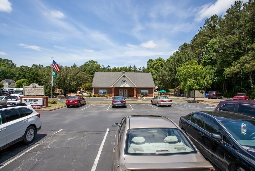 Parking lot with cars in front of a building with a sign and flag