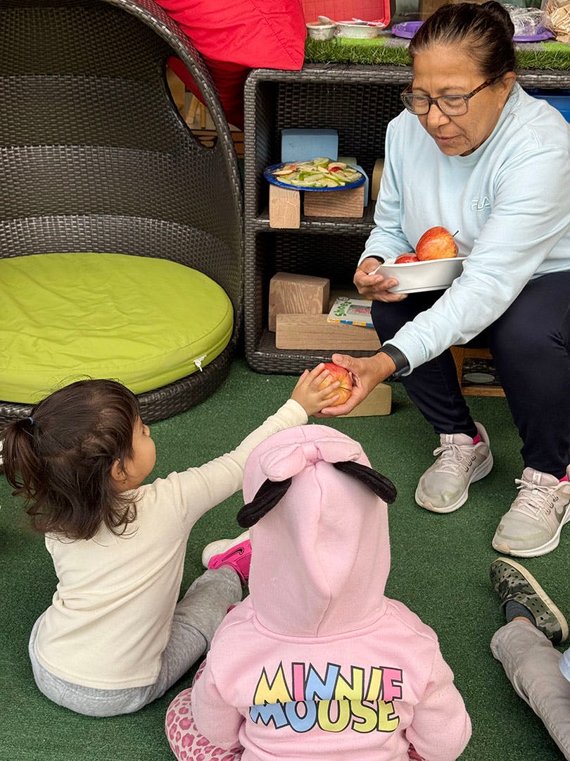 Adult handing an apple to a child