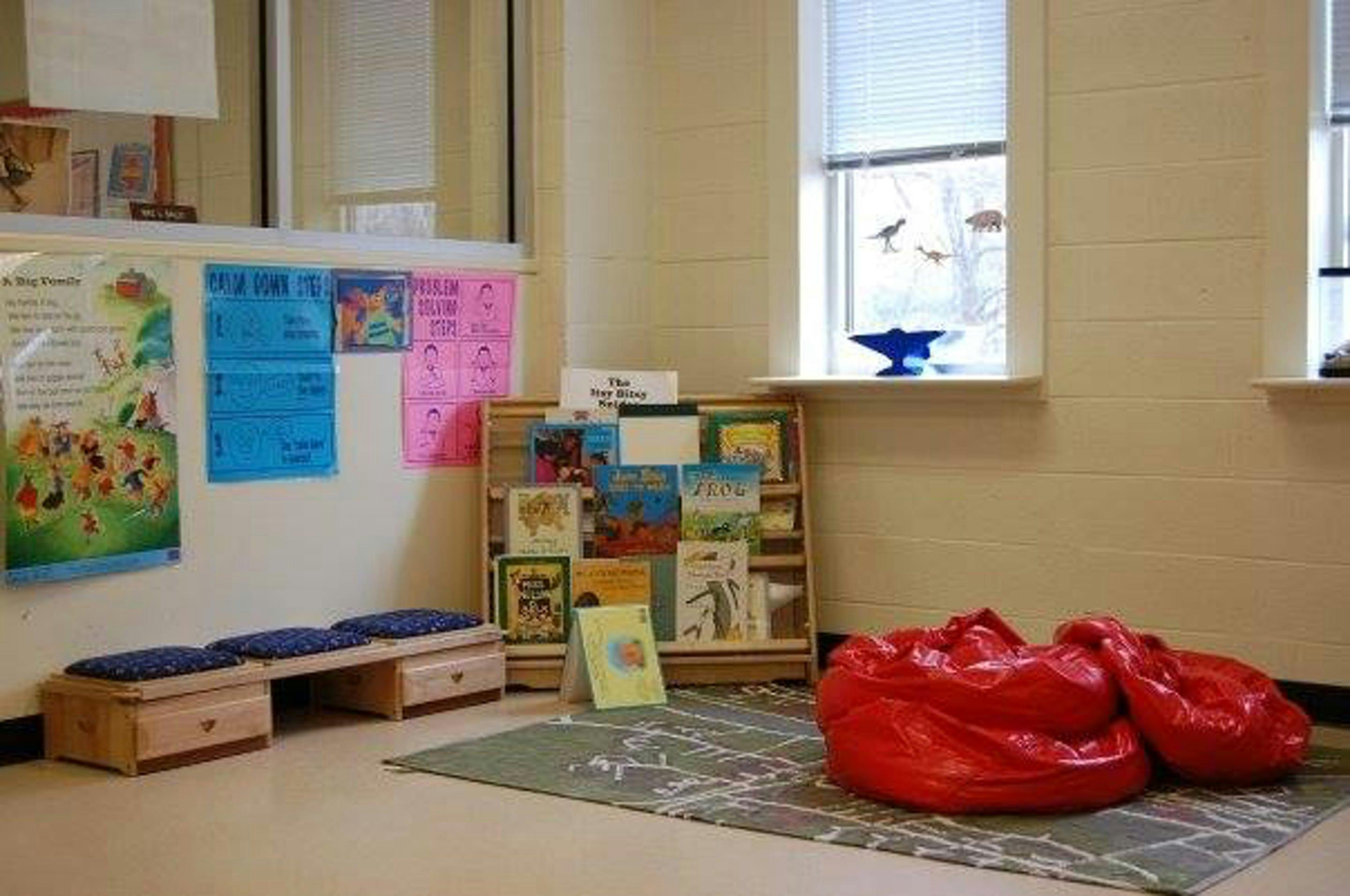 Children's reading nook with a bookshelf, bench, and red beanbag chairs