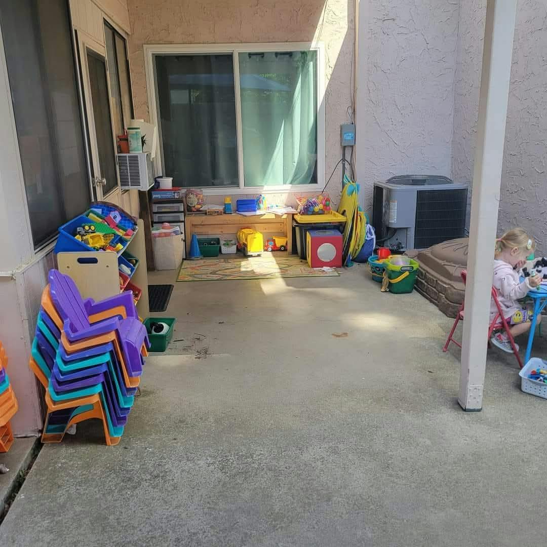 Child sitting at a small table with toys on a patio