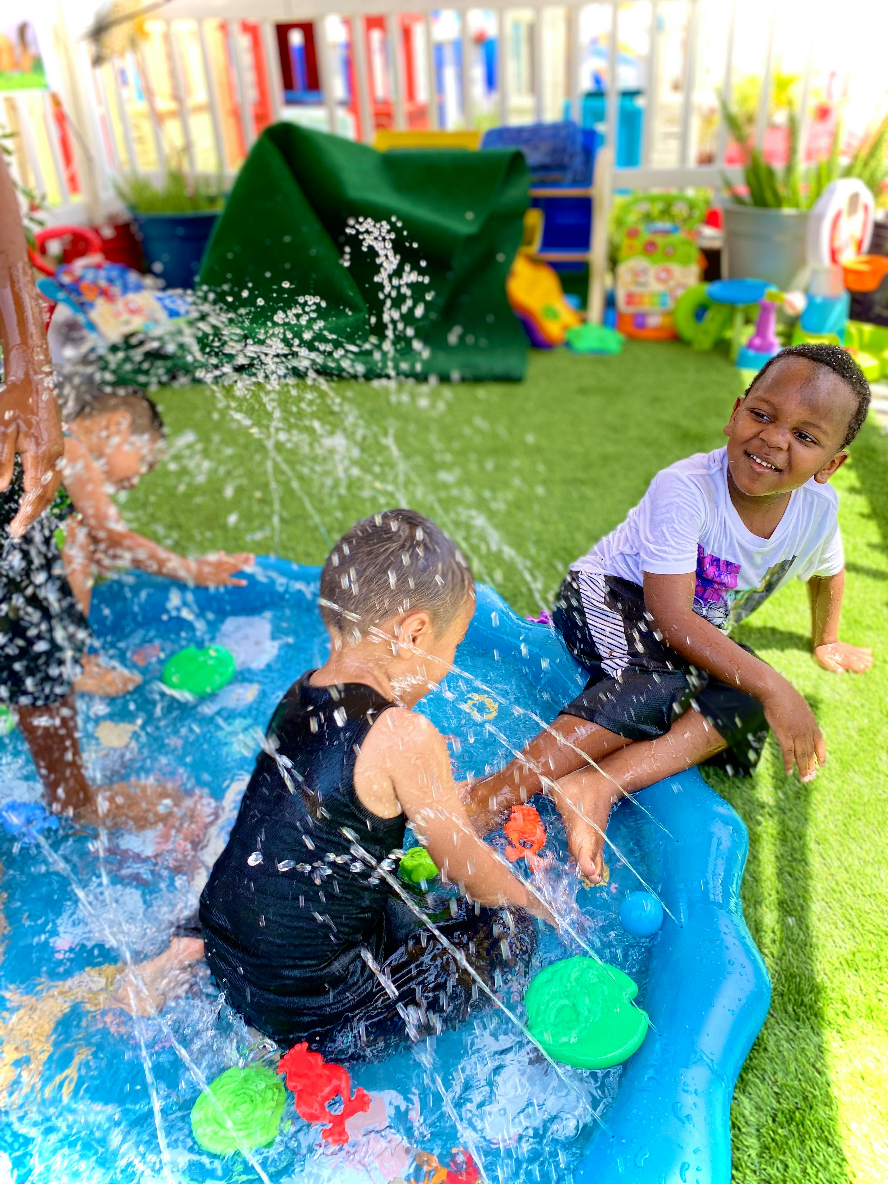 Children playing in a blue splash pad with water spraying
