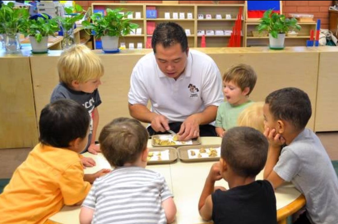 Person demonstrating an activity to children in a classroom
