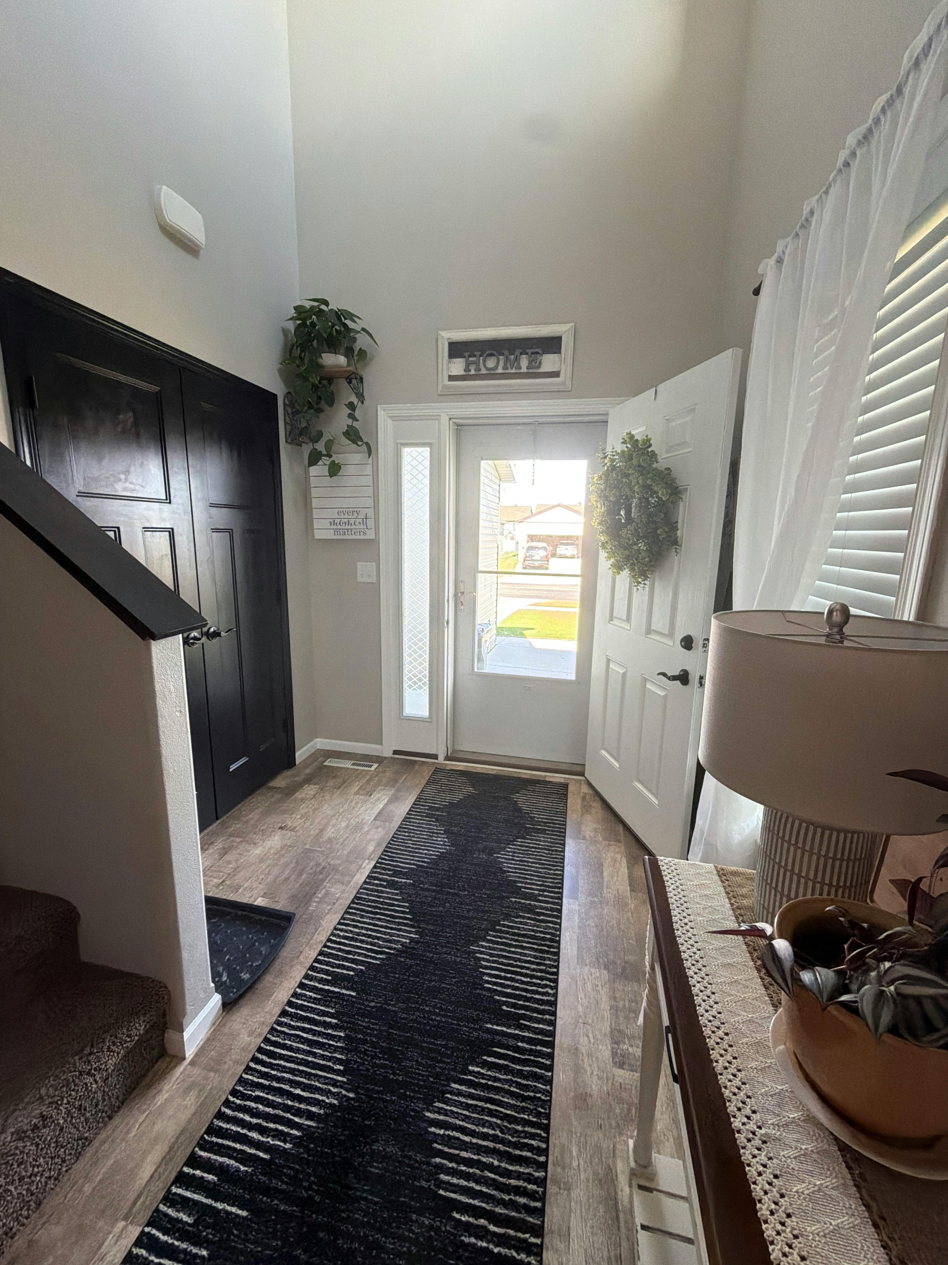 Looking down a staircase toward an open front door with a wreath
