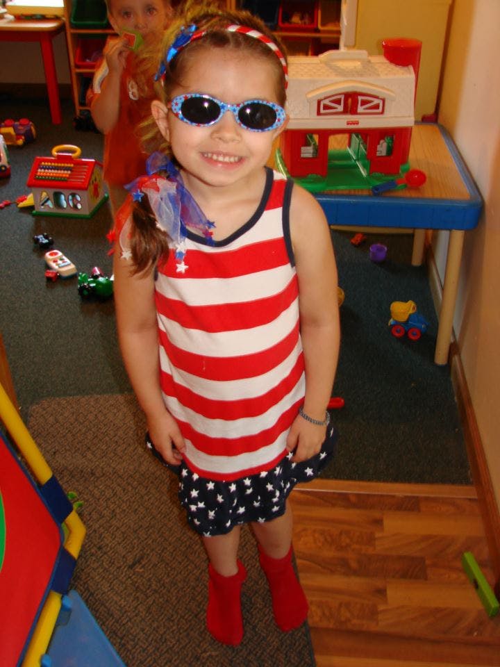 Child wearing sunglasses and a red, white, and blue outfit