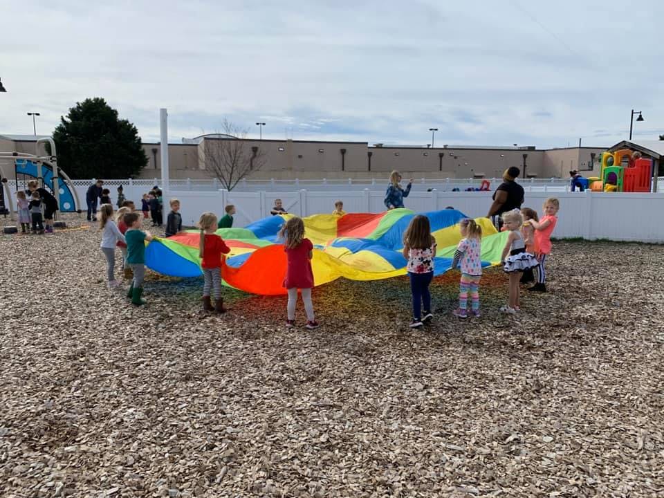 Children playing with a colorful parachute outdoors