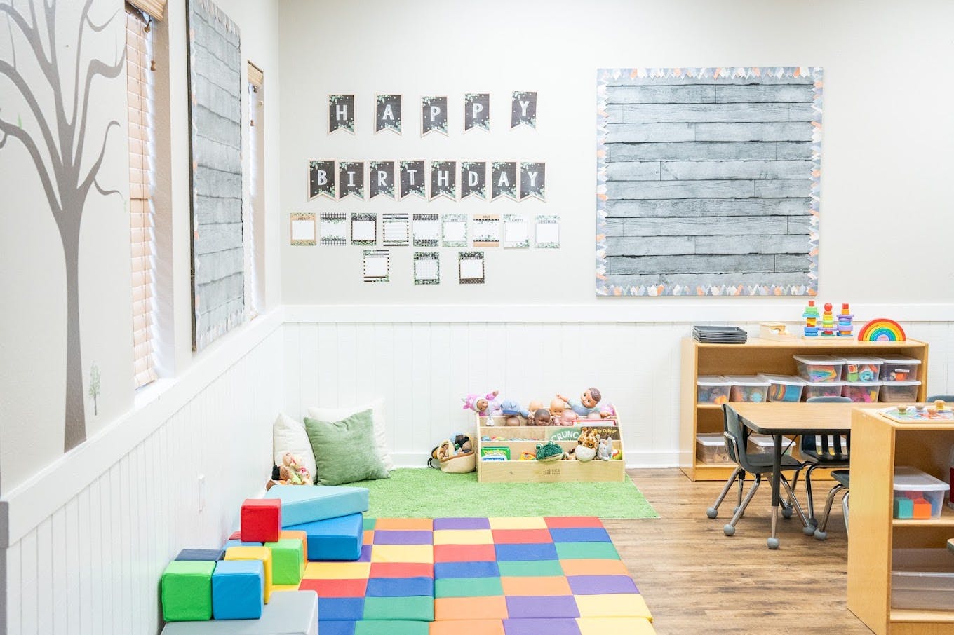 Classroom with toy storage and colorful floor mats under a birthday banner