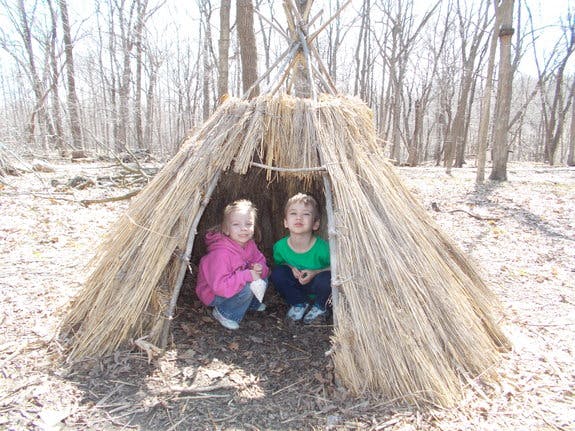 Two children sitting inside a straw hut