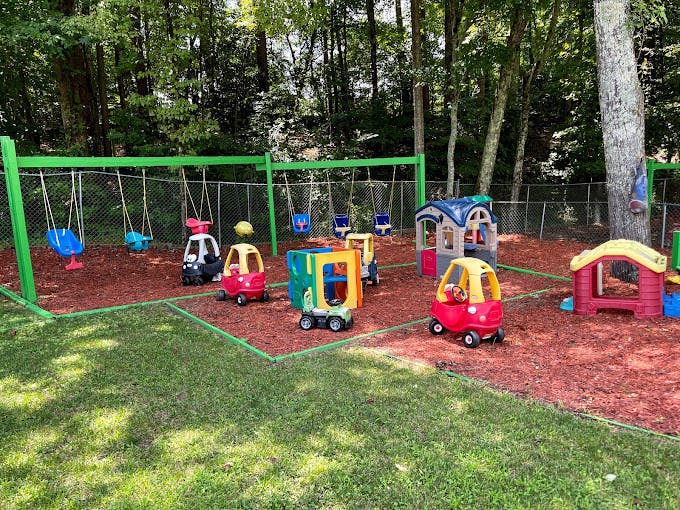 Outdoor playground with swings, playhouses, and ride-on toys