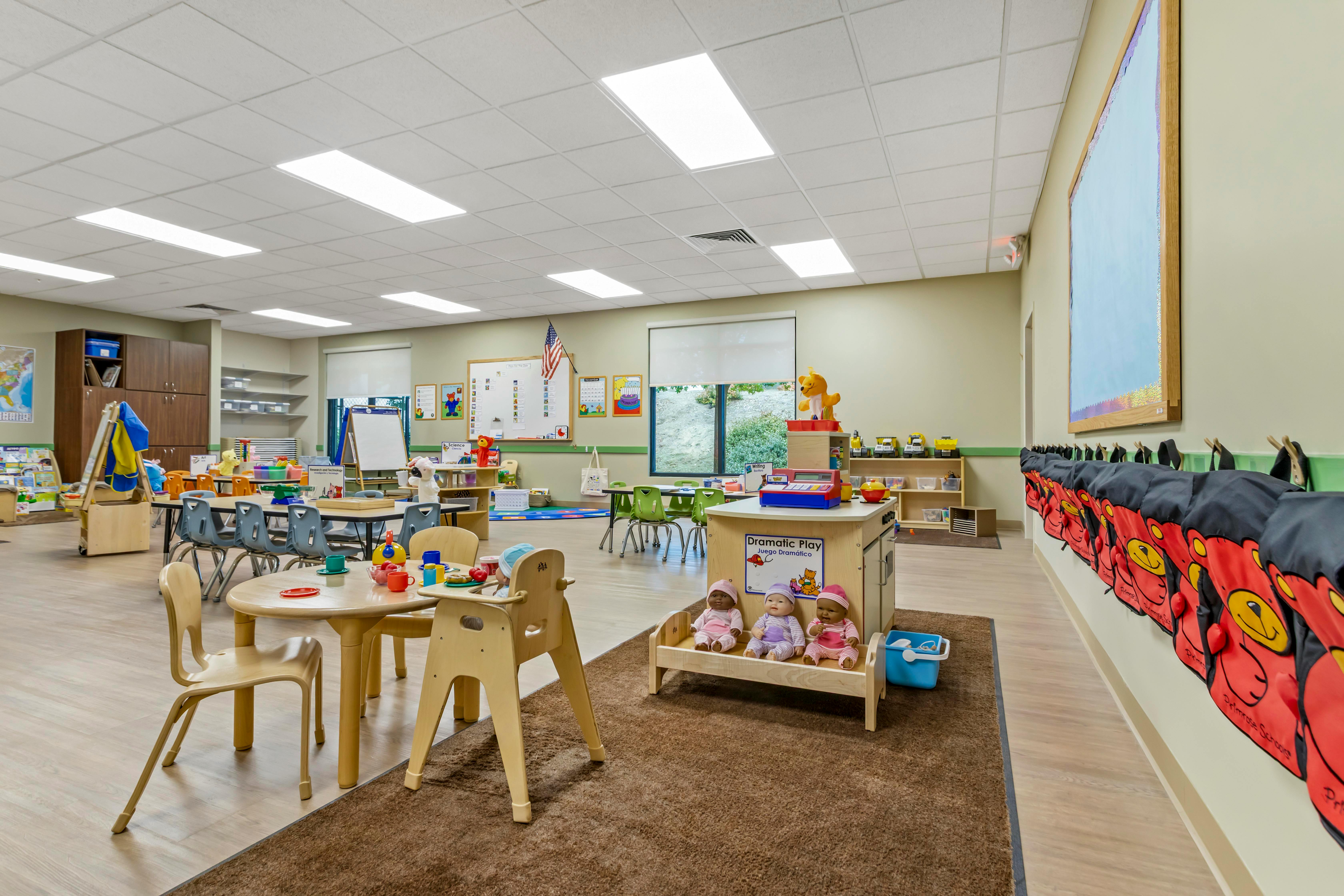 An empty early childhood classroom with multiple play areas and tables