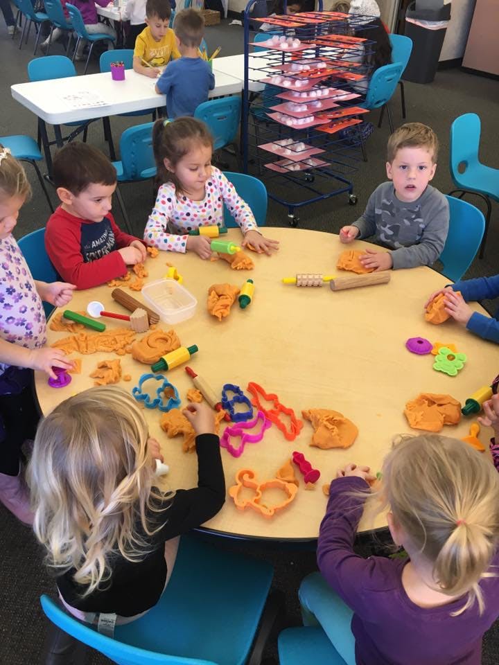 Children playing with modeling clay at a round table
