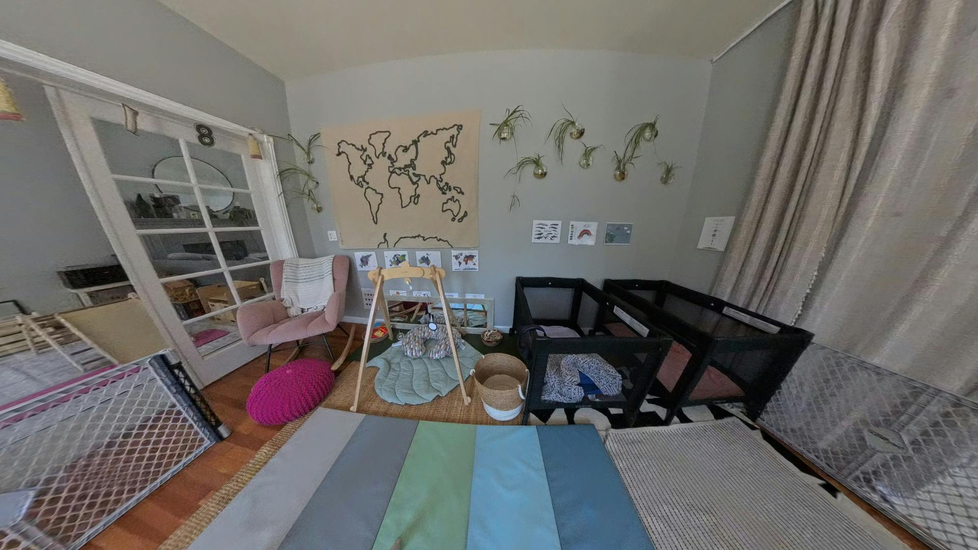 Room with multiple cribs, a rug, and a map on the wall