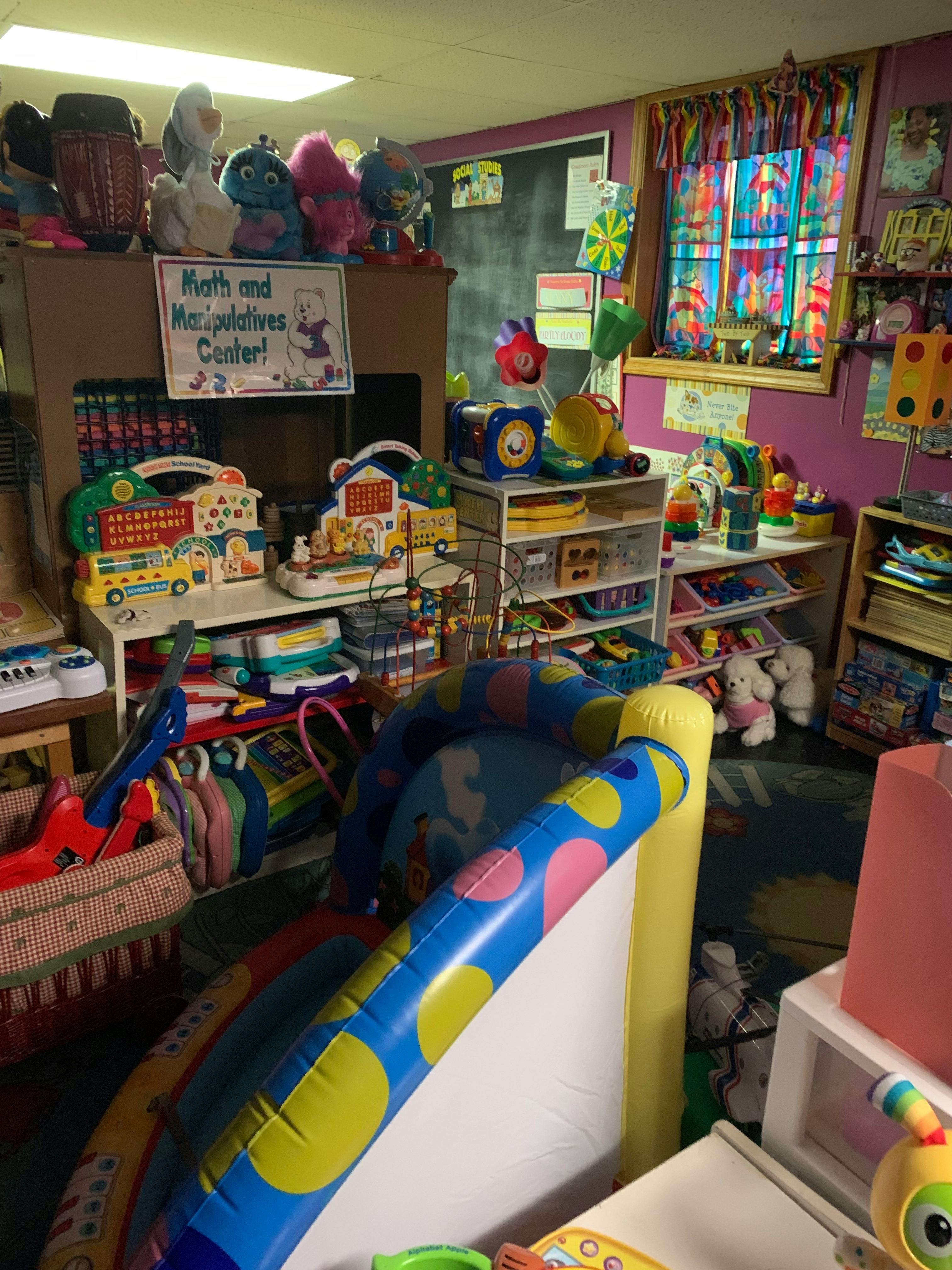 A room filled with toys and shelves, with a sign that reads "Math and Manipulatives Center"