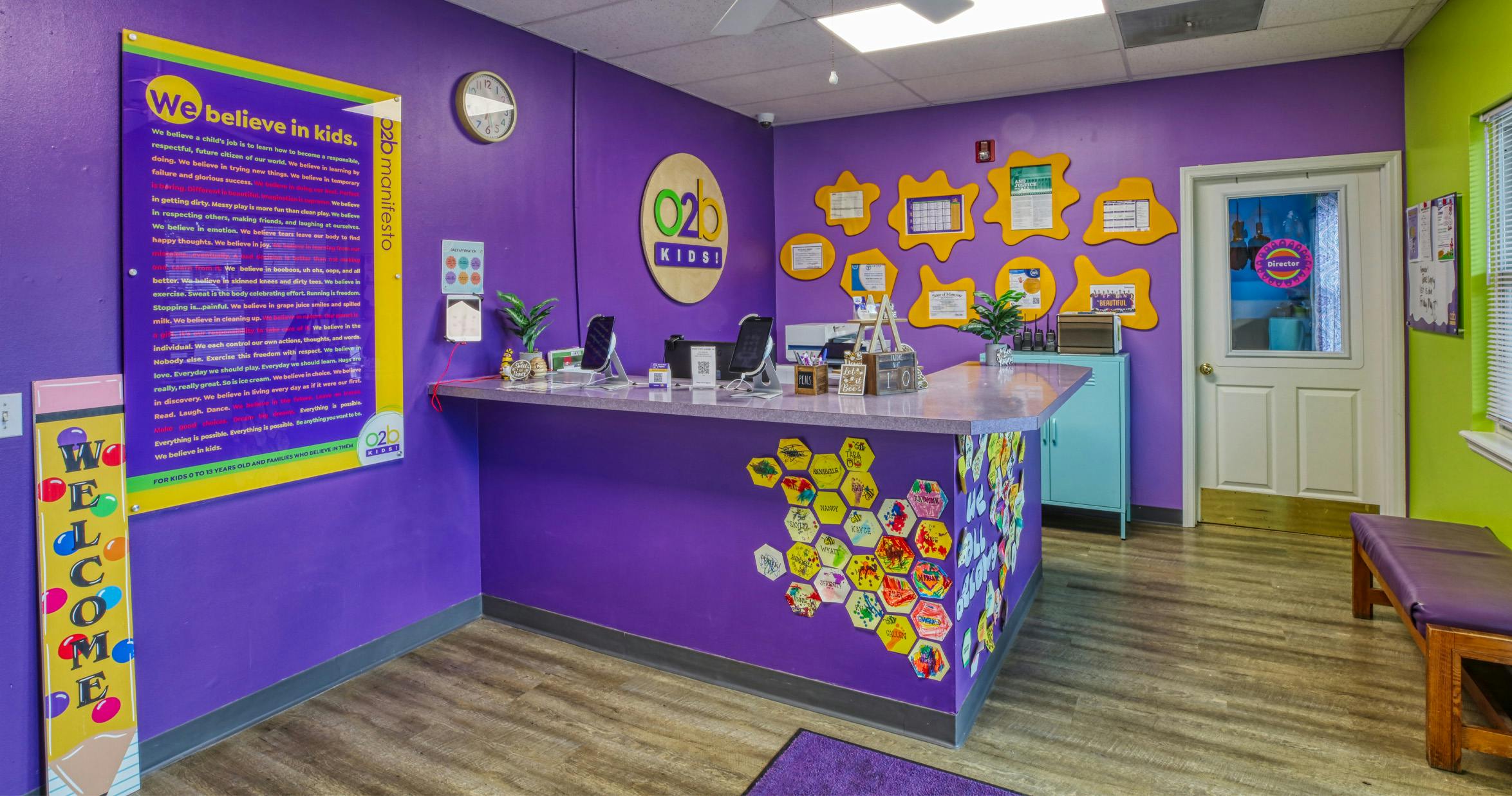 Reception desk inside a childcare facility with purple walls and a welcome sign
