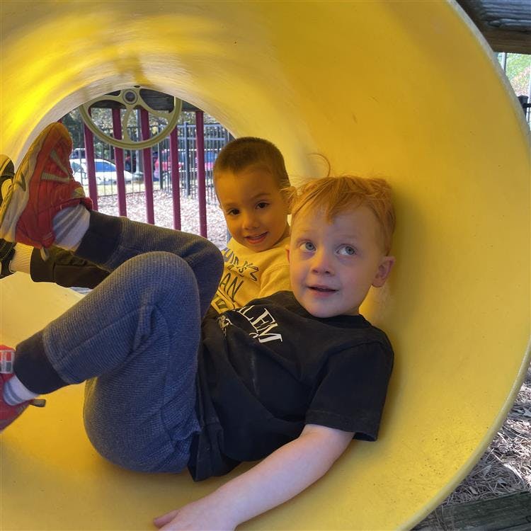 Two children inside a yellow tunnel slide