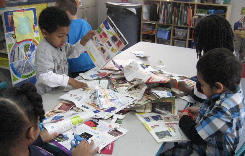 Children looking at papers and magazines at a table