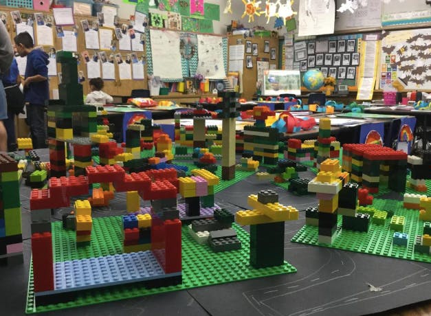 Lego creations on green baseplates in a classroom