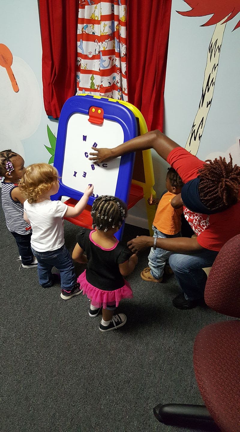 Adult and children interacting with a magnetic letter board