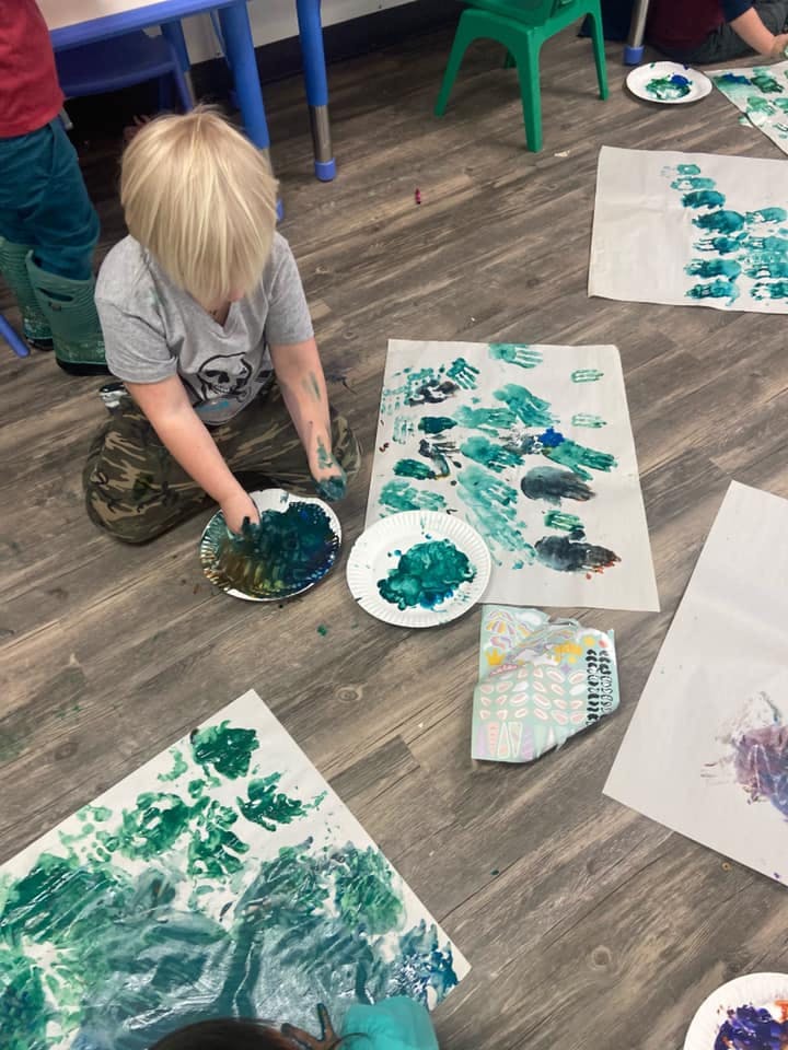 Child finger painting on the floor