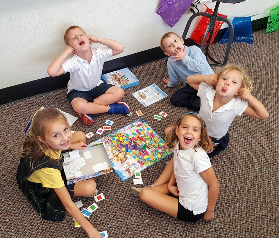 Five children sitting on the floor playing a board game