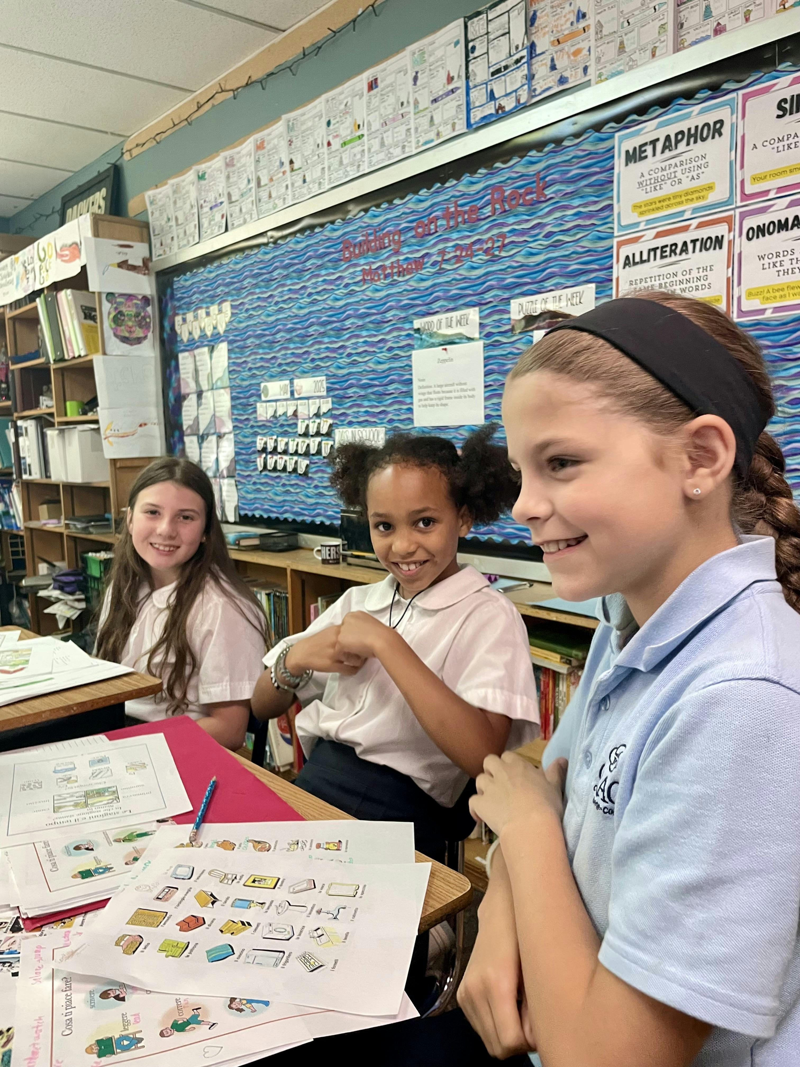 Three children sitting at desks in a classroom