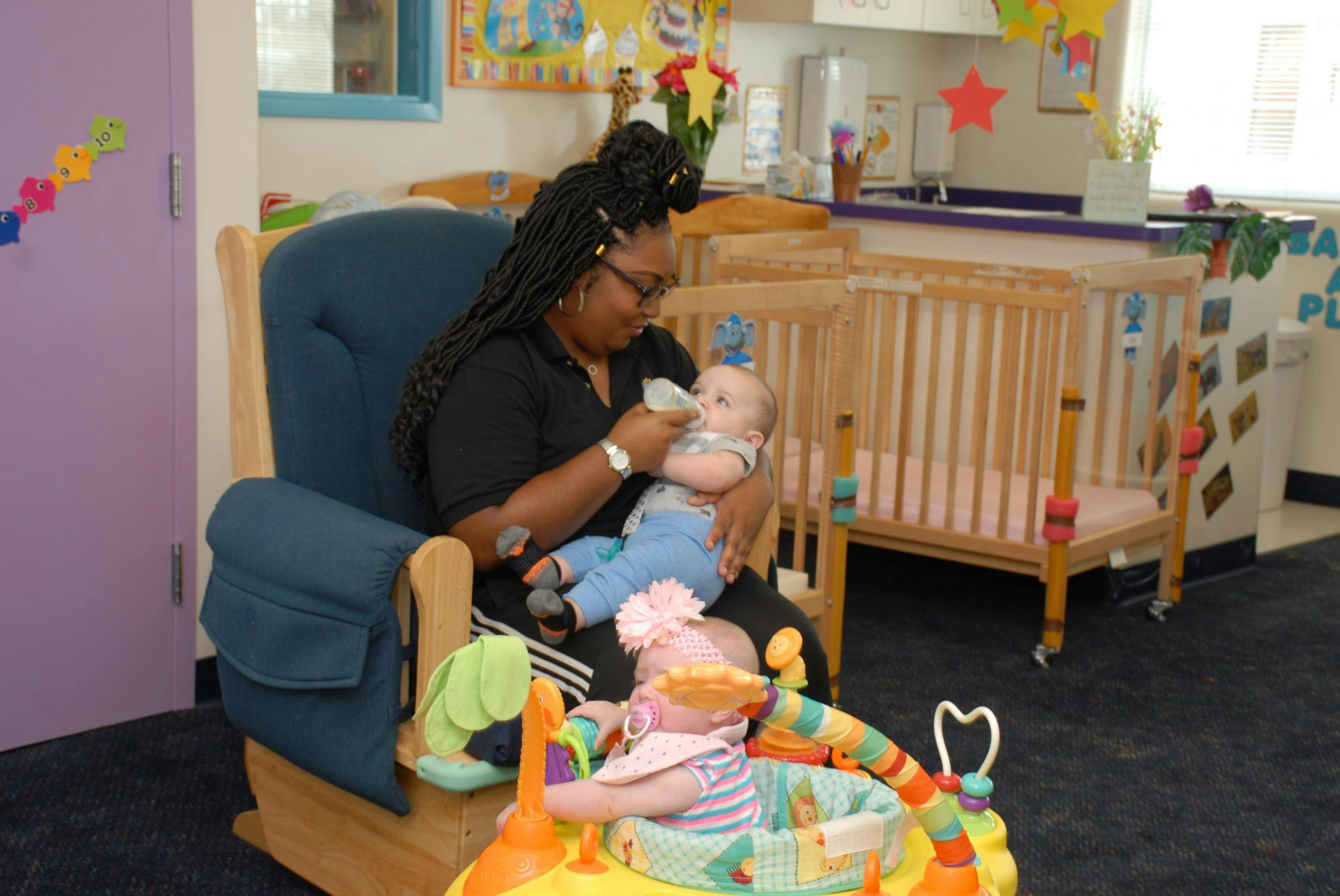 Person feeding a child with a bottle in a rocking chair
