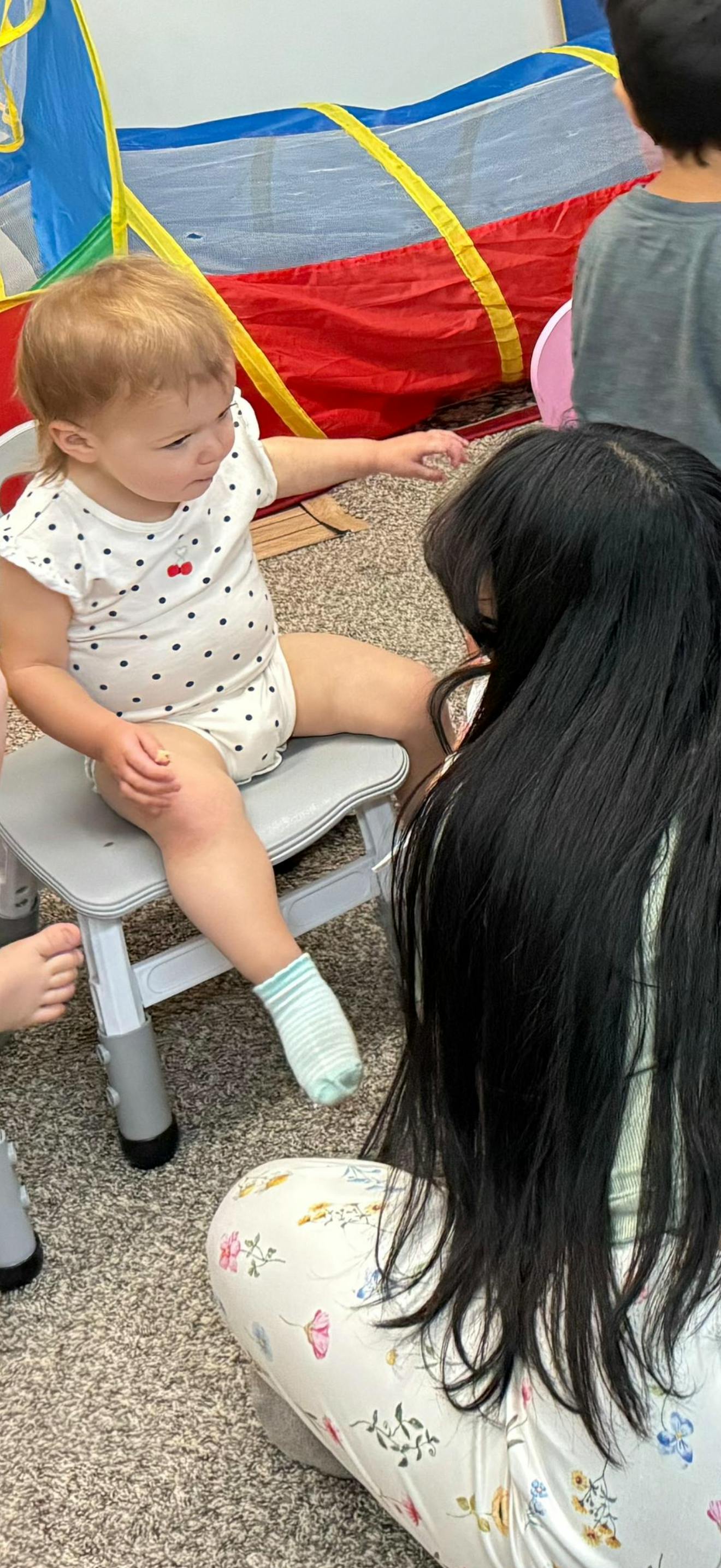 Child sitting on a small chair interacting with another person