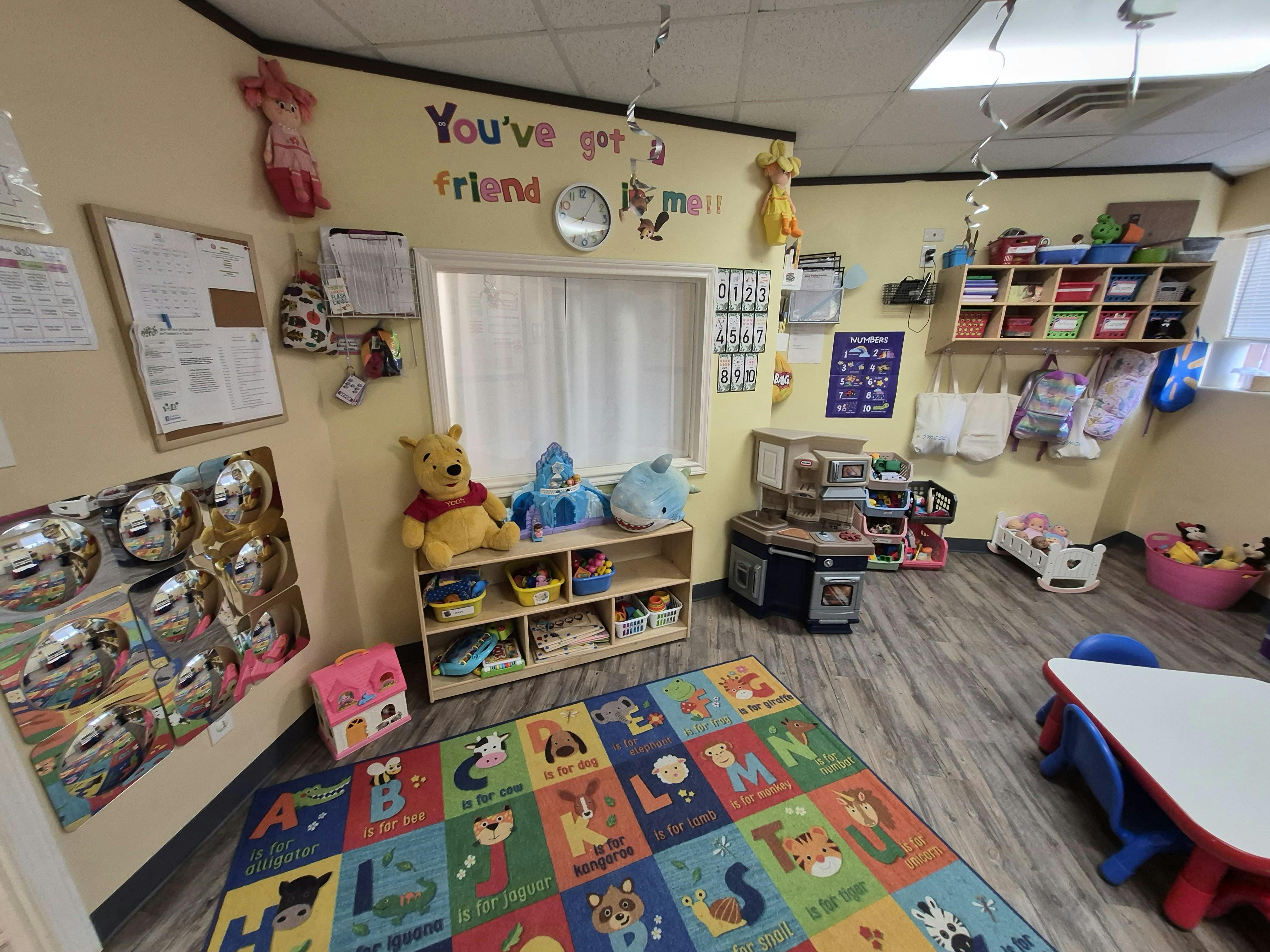 Playroom with alphabet rug, toy kitchen, and shelving with stuffed animals