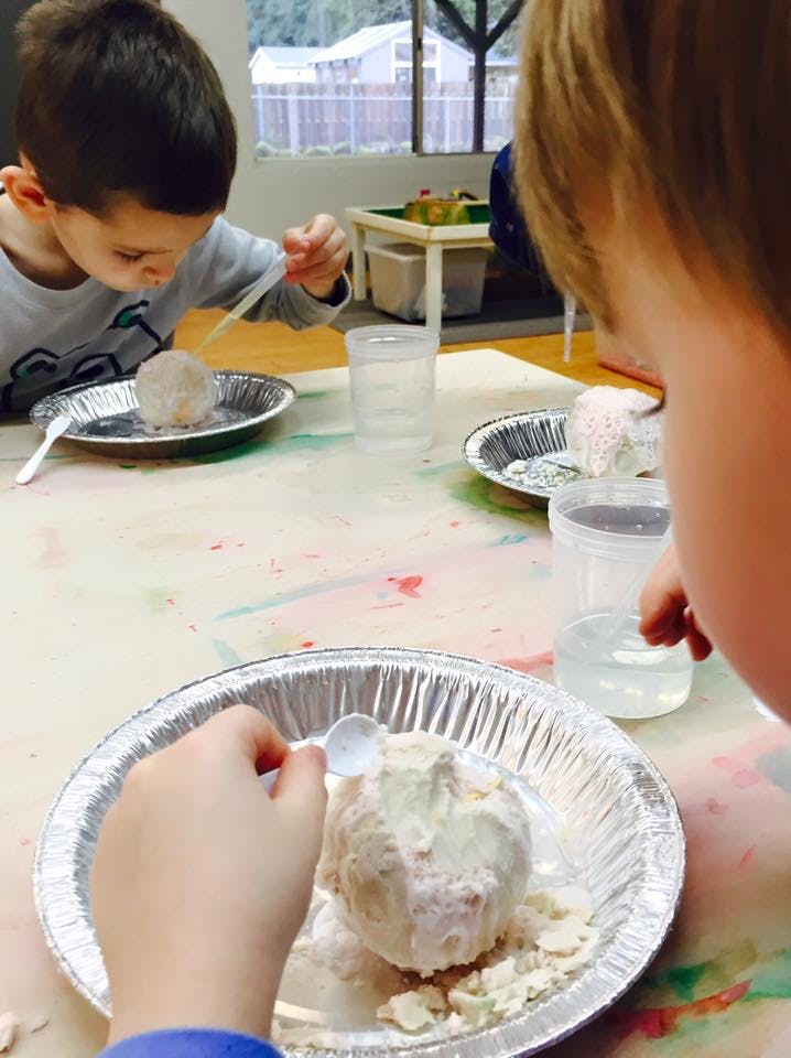 Two children doing a science experiment with white powder and liquid