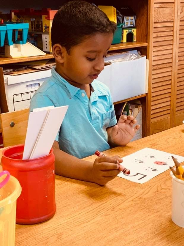 Child coloring on a paper at a wooden table