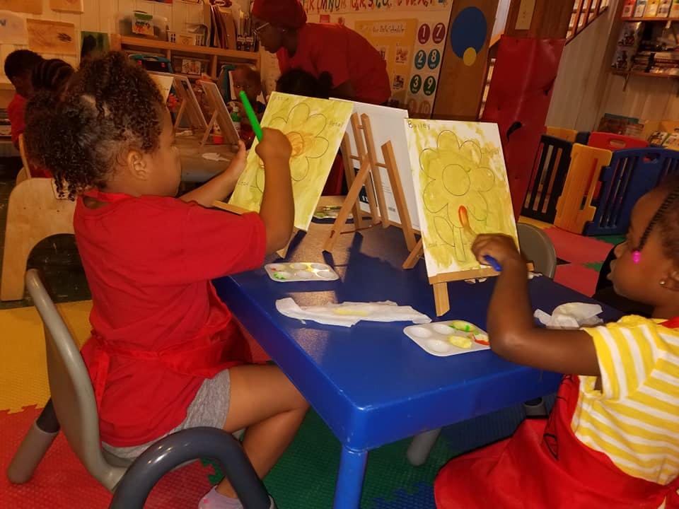 Two children painting at easels on a blue table