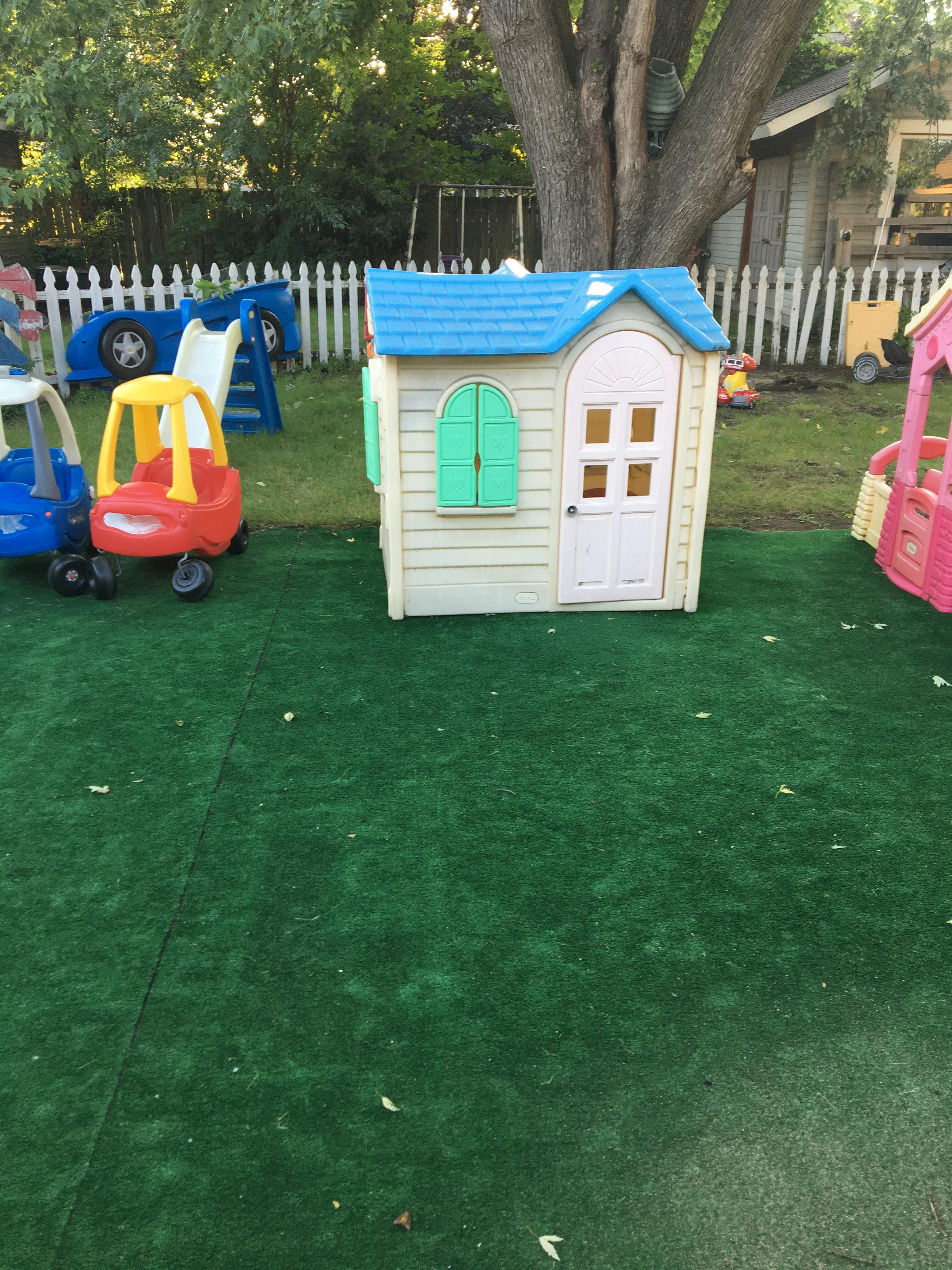 Playhouse and toy cars on artificial grass