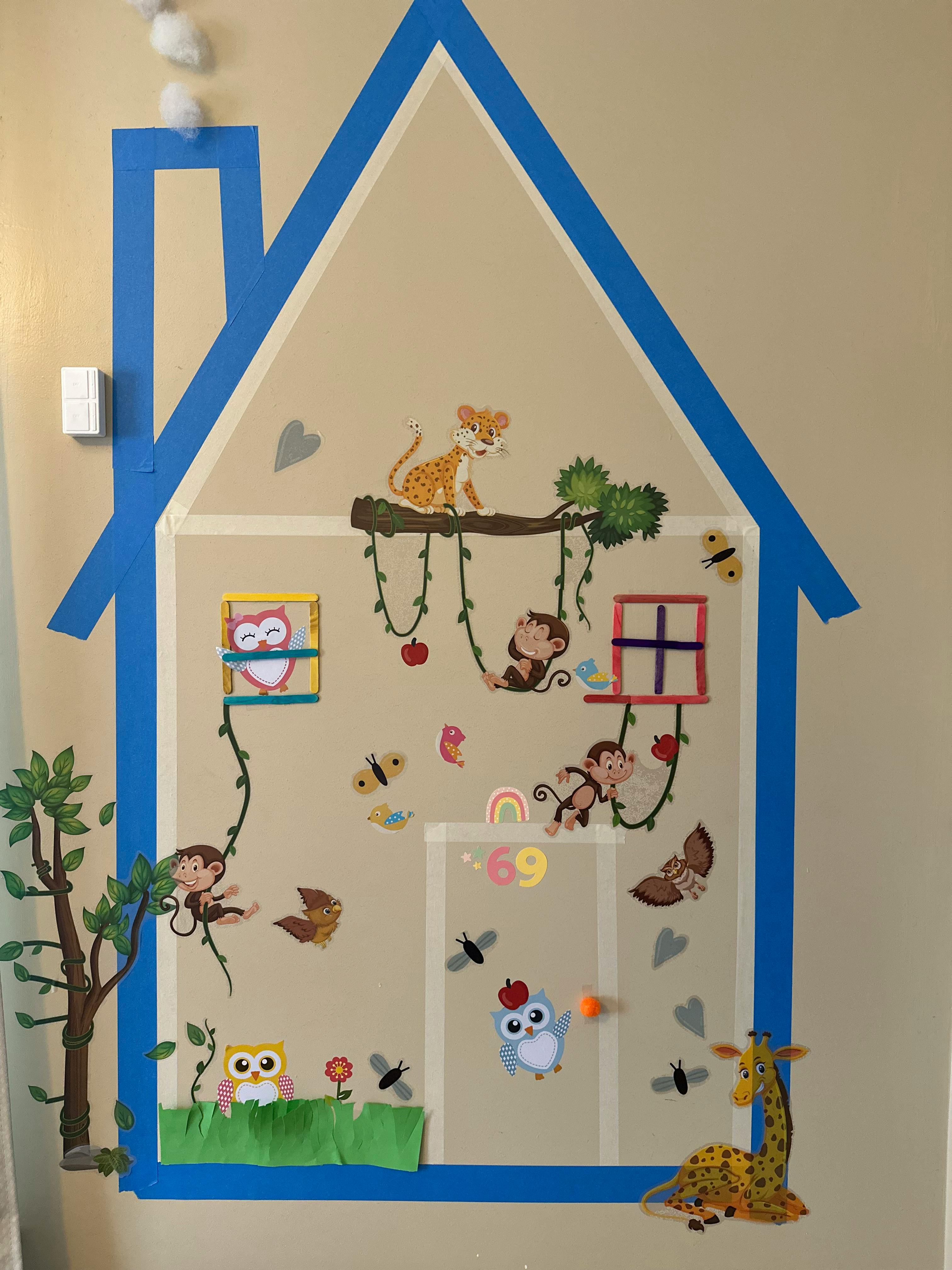 Wall decoration of a house with animal stickers including monkeys, owls, and a giraffe
