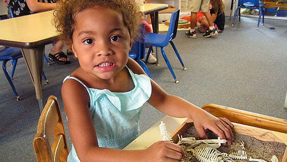 Child at a table with a toy skeleton