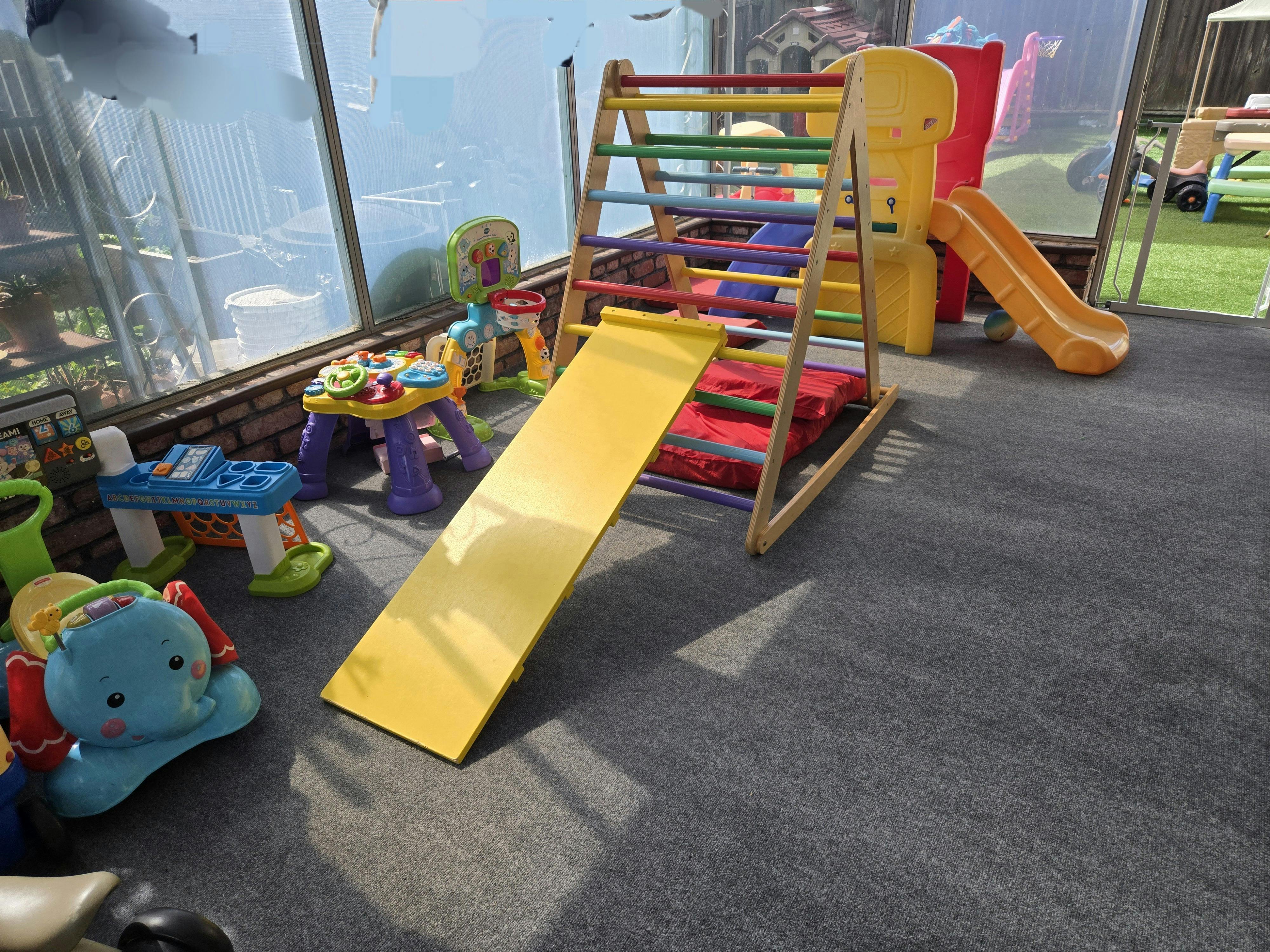 Colorful indoor play area with climbing frame, slide, and various toys