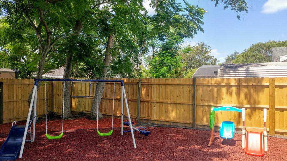 Playground with swings, slide, and a wooden fence