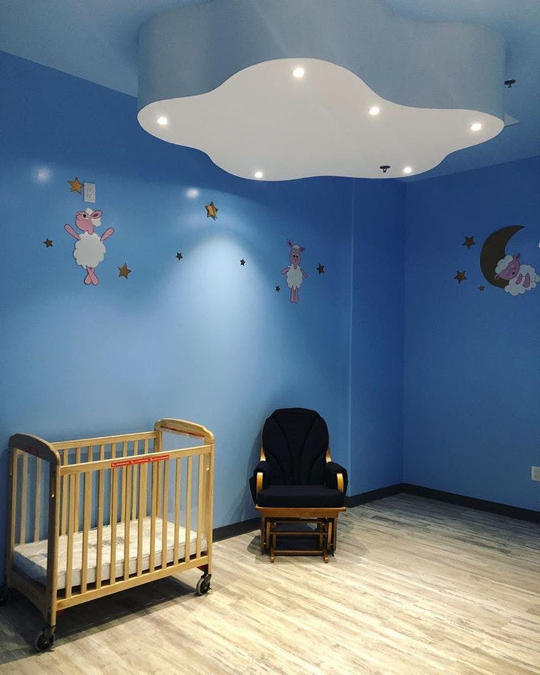 Nursery room with a crib, rocking chair, and cloud-shaped ceiling light