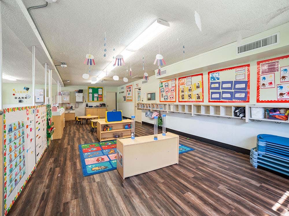 empty preschool classroom with play mats and cubbies