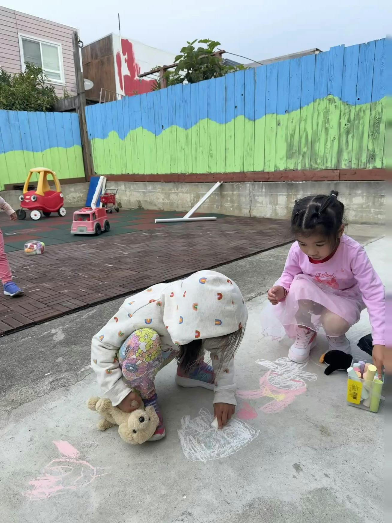 Two children drawing with chalk on pavement