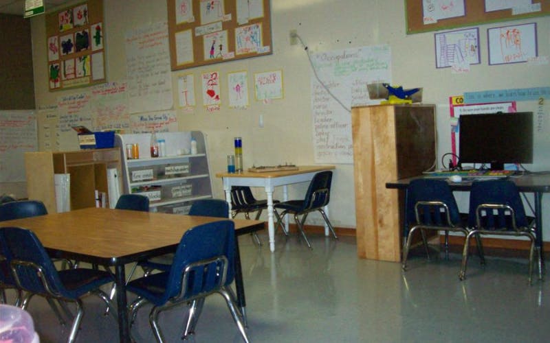 Classroom with child-sized tables and chairs, computer, and student artwork on walls