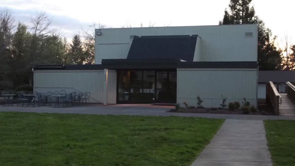 Building exterior with a dark roof over the entrance and a grassy lawn