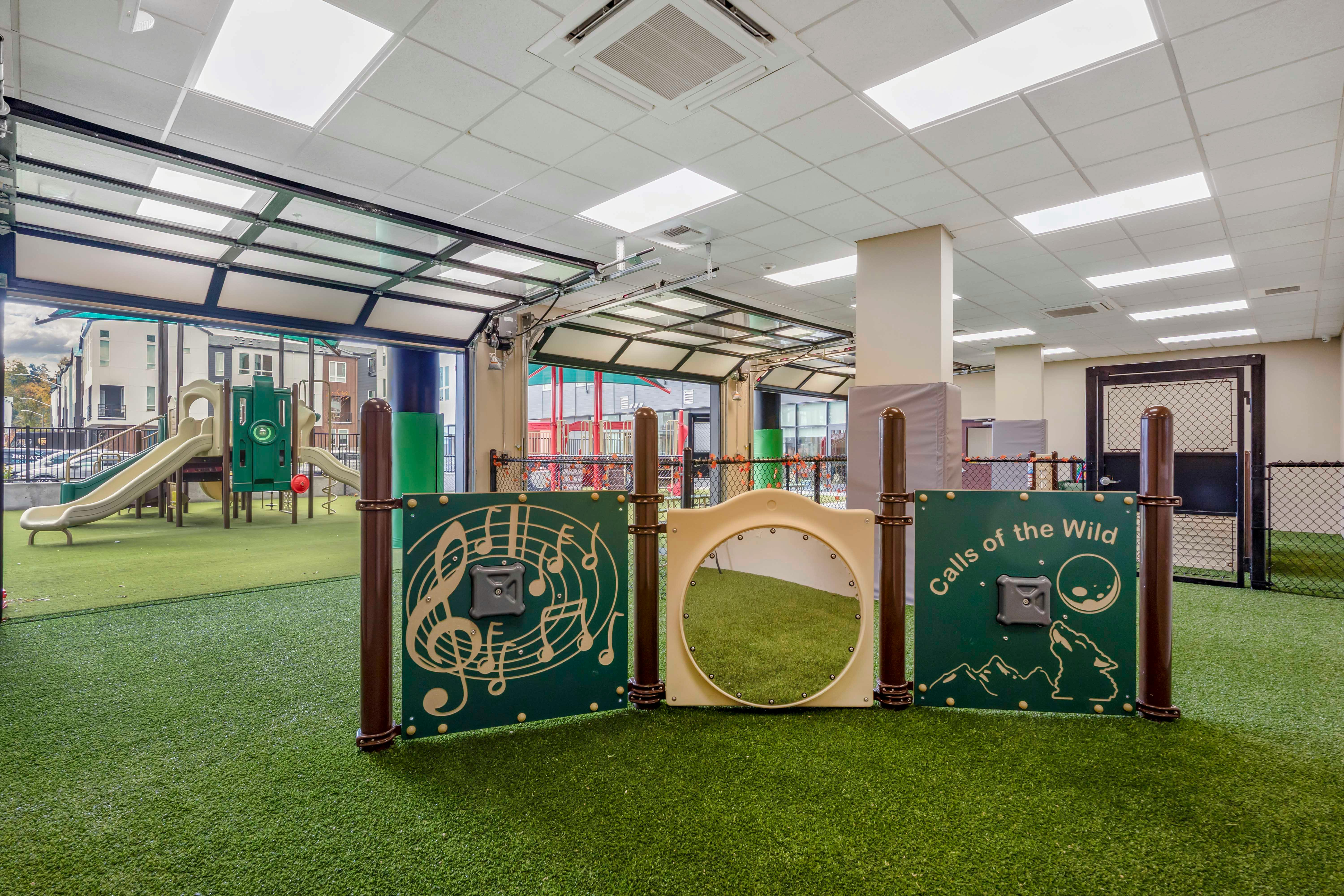 Indoor playground with turf ground, slides, and activity panels