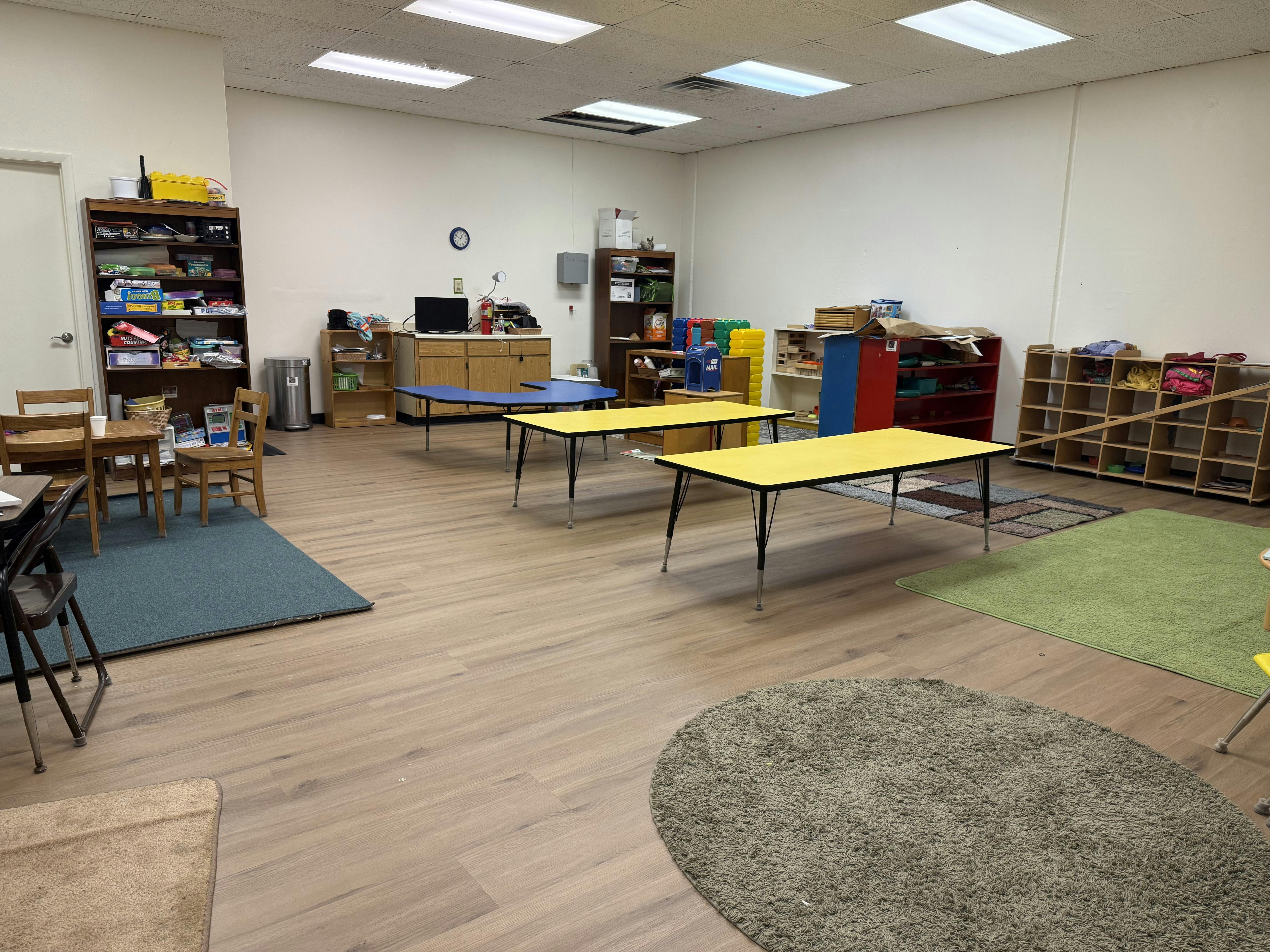 Classroom with yellow tables and various shelves