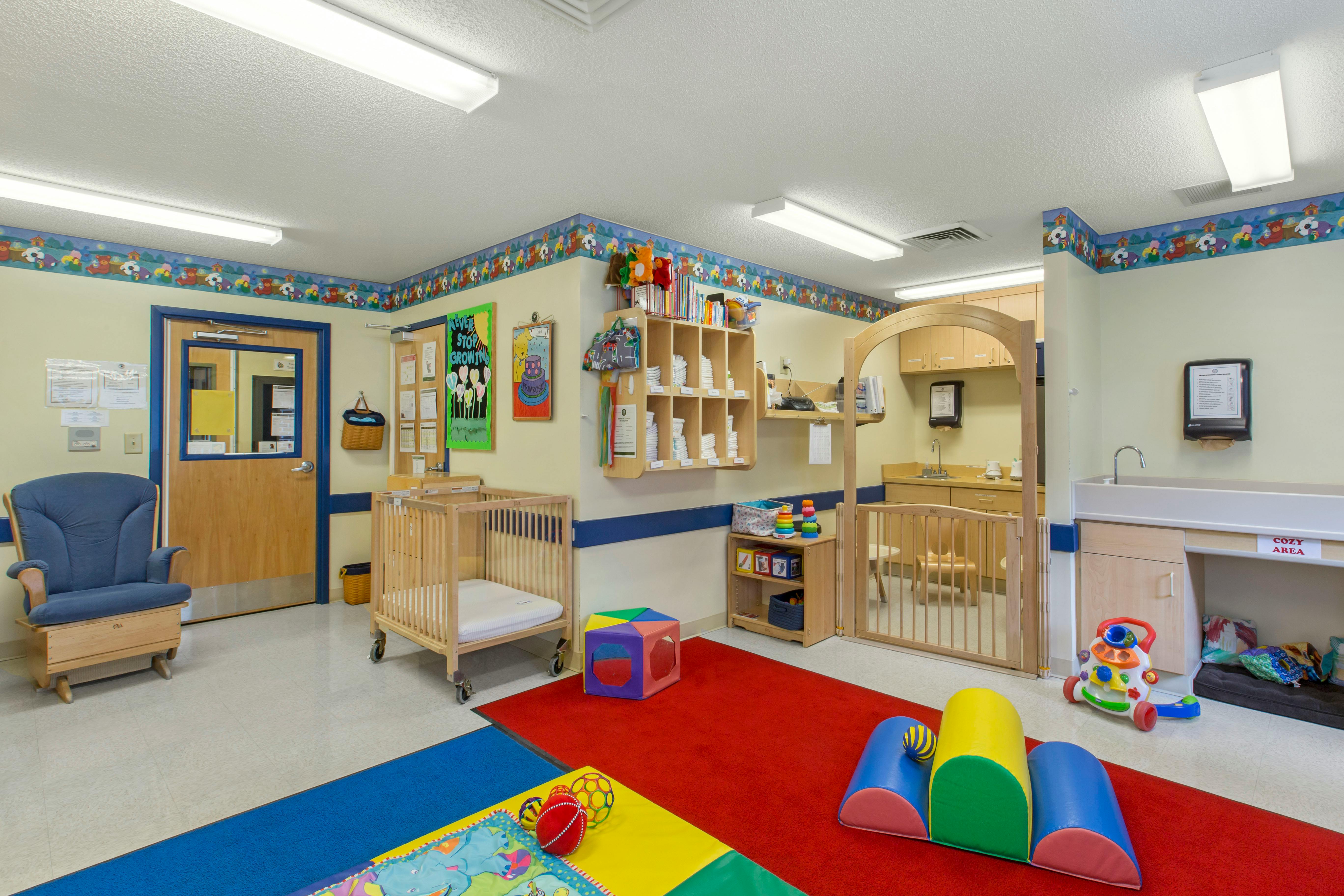 Baby room with cribs, play mats, rocking chair, and changing station