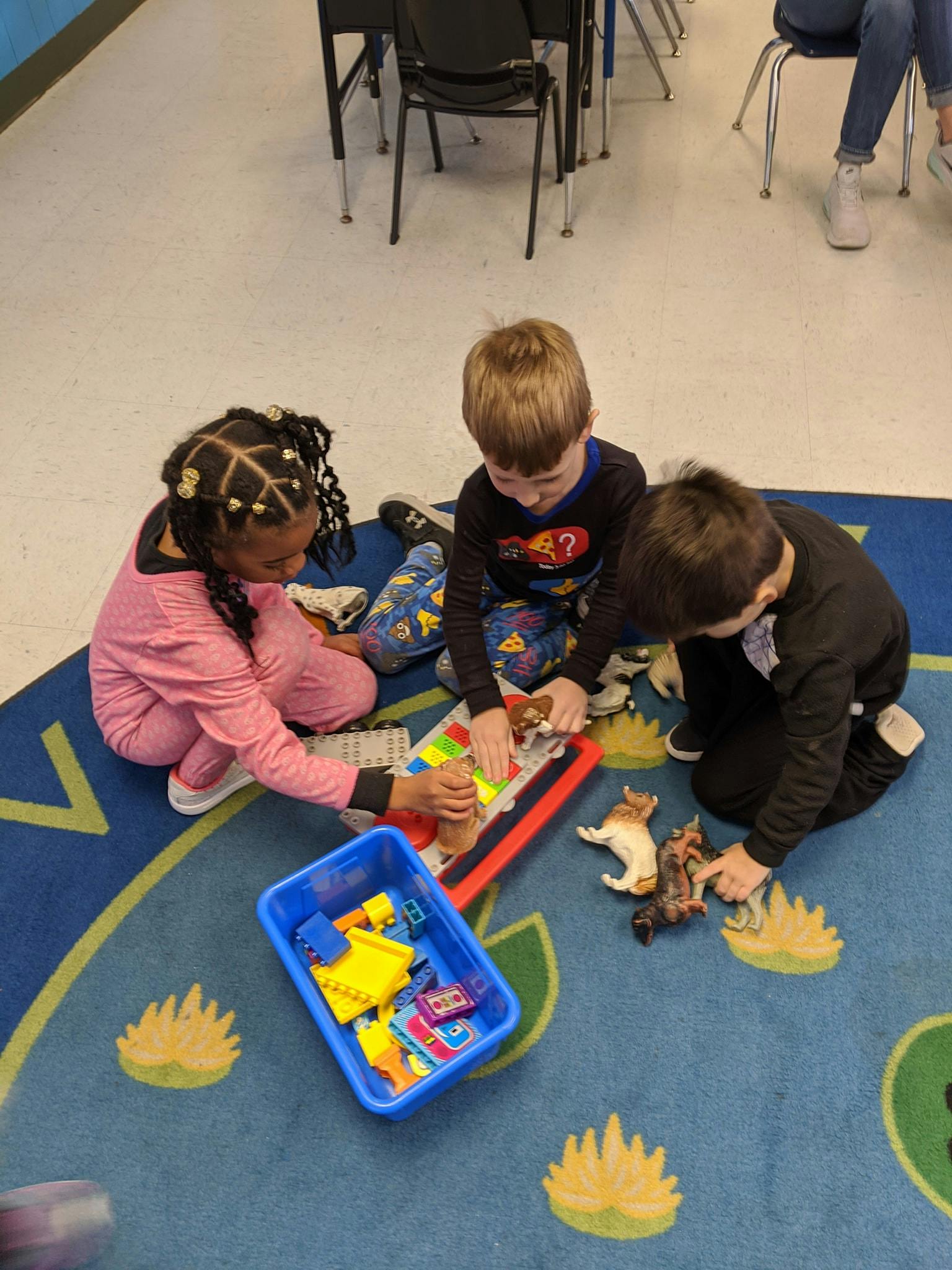 Three children playing with toys on a rug
