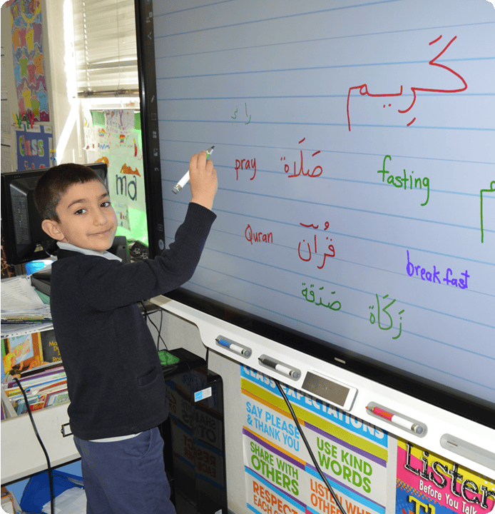 Child writing on an interactive whiteboard with a marker