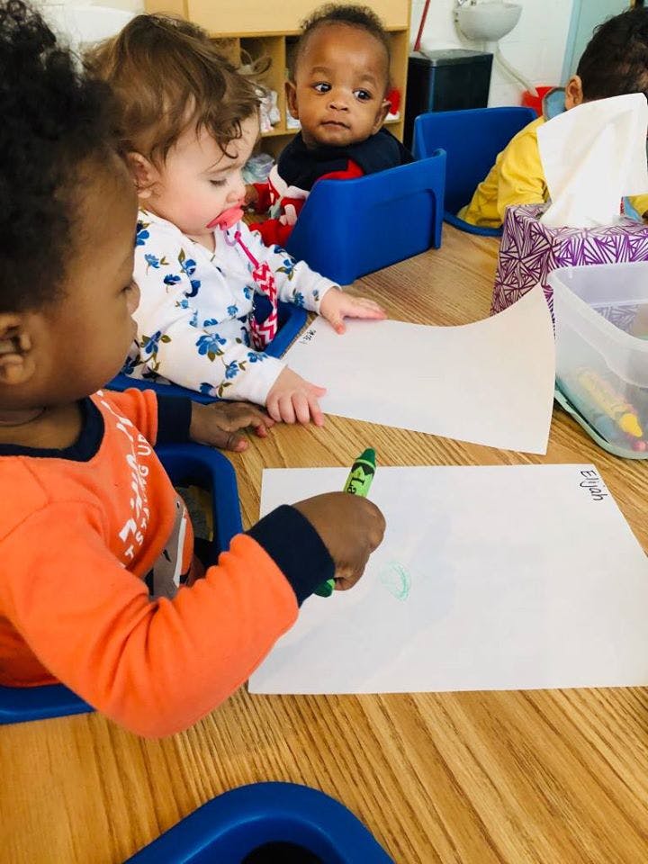 Three children drawing with crayons at a table