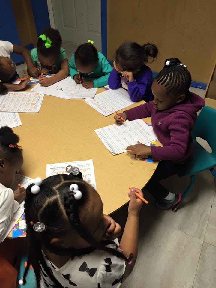 Children sitting around a table writing on papers