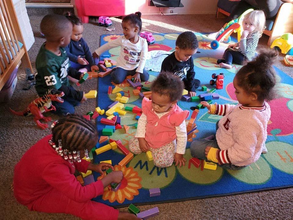 Multiple children playing with colorful blocks on a rug