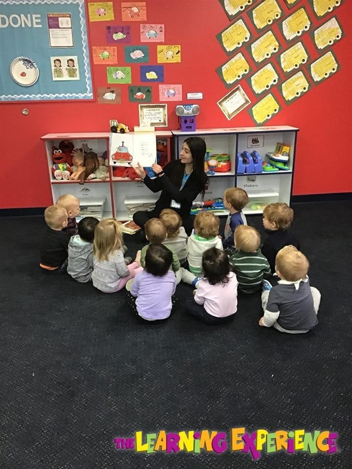 Adult reading a book to a group of children in a classroom